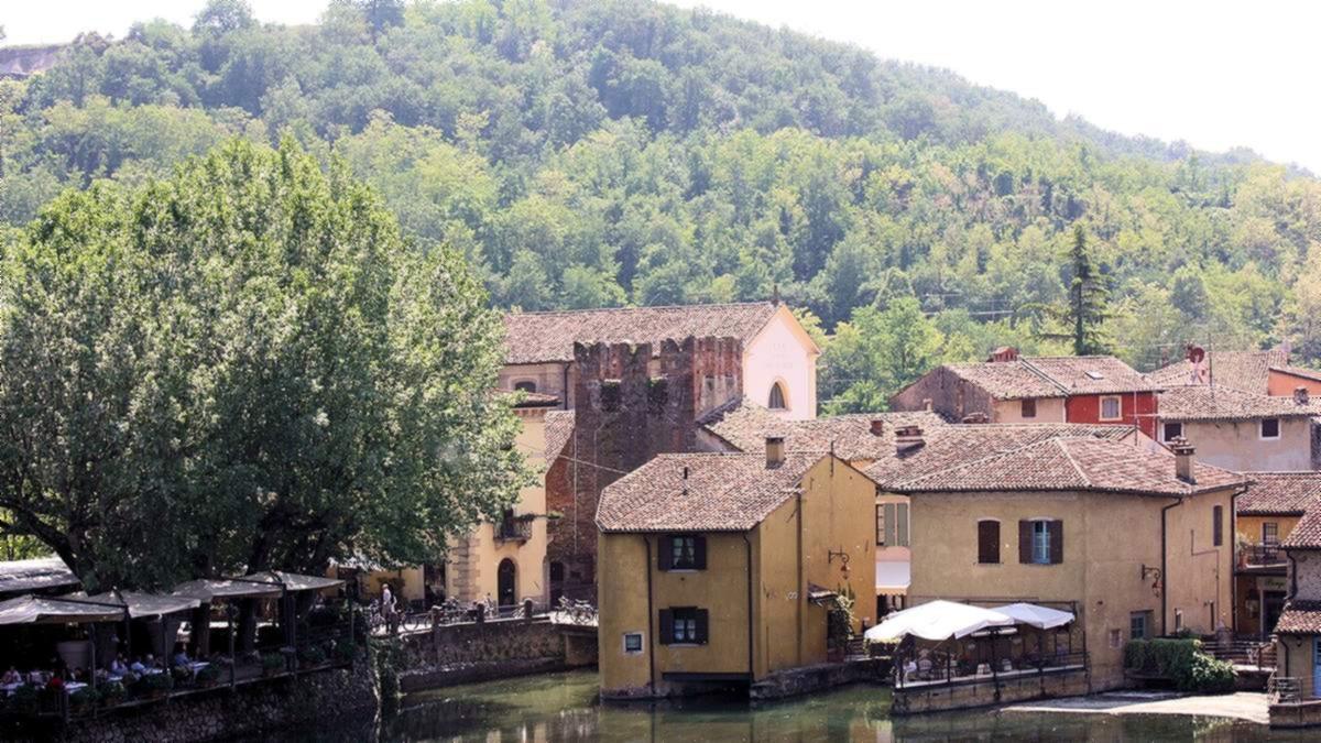 Alte Mühlenhäuser am Fluss Mincio in Borghetto bei Valeggio sul Mincio, dahinter bewaldete Hügel