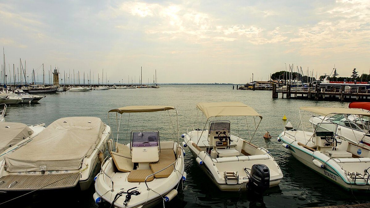 Alter Hafen von Desenzano del Garda mit Motorbooten und dem kleinen Leuchtturm an der Mole