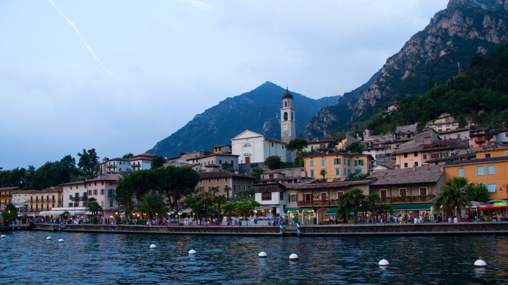 Limone sul Garda am Abend vom Wasser aus, Häuser am Hang, Kirchturm und dahinter die steile Bergwand