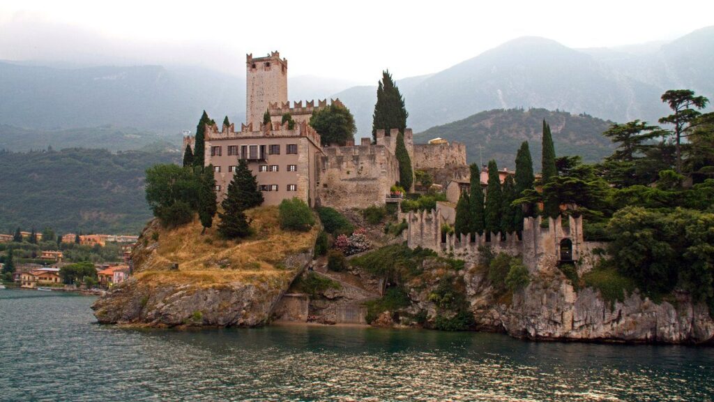Castello Scaligero in Malcesine auf einem Felsen über dem Gardasee, dahinter die Hänge des Monte Baldo