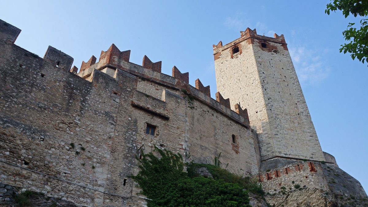 Wehrmauer mit Zinnen und heller Bergfried des Castello Scaligero in Malcesine von unten gesehen