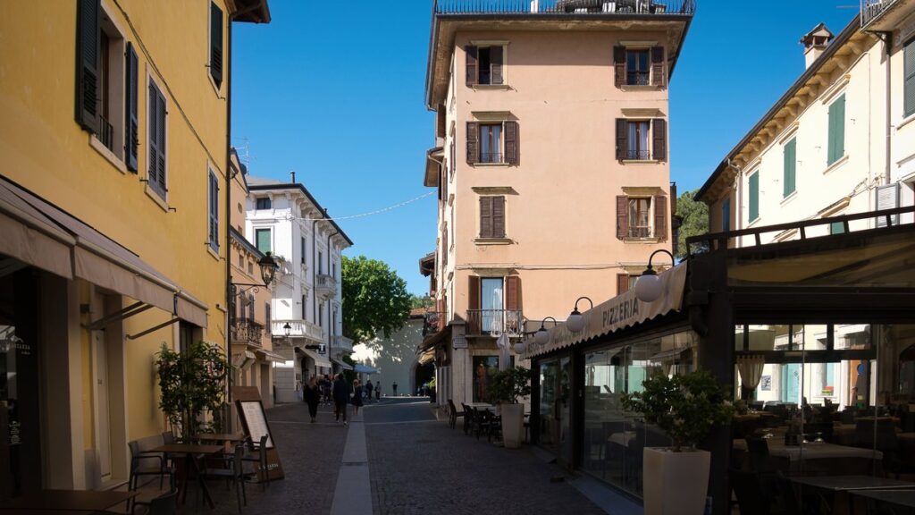 Sonnige Gasse in der Altstadt von Peschiera del Garda mit Läden und Pizzeria