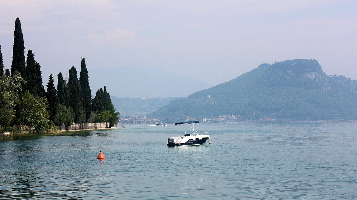 Blick von Punta San Vigilio über den Gardasee zur Rocca di Garda mit Zypressenufer