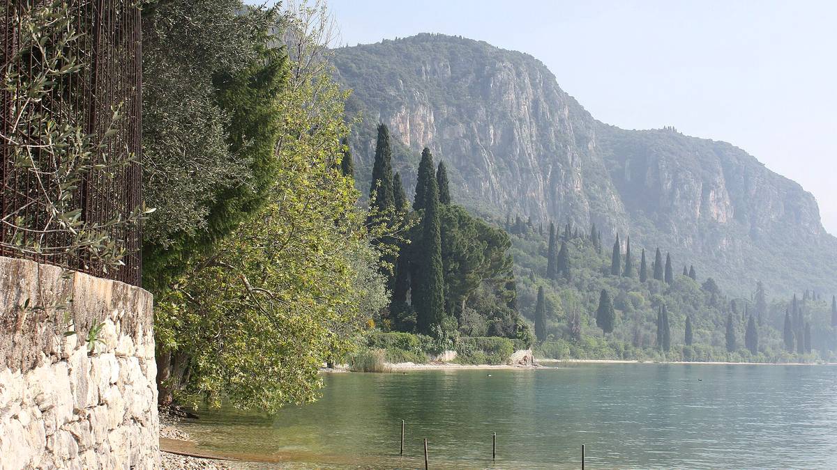 Bucht bei Punta San Vigilio mit hellem Uferstreifen, Zypressen und der Rocca di Garda