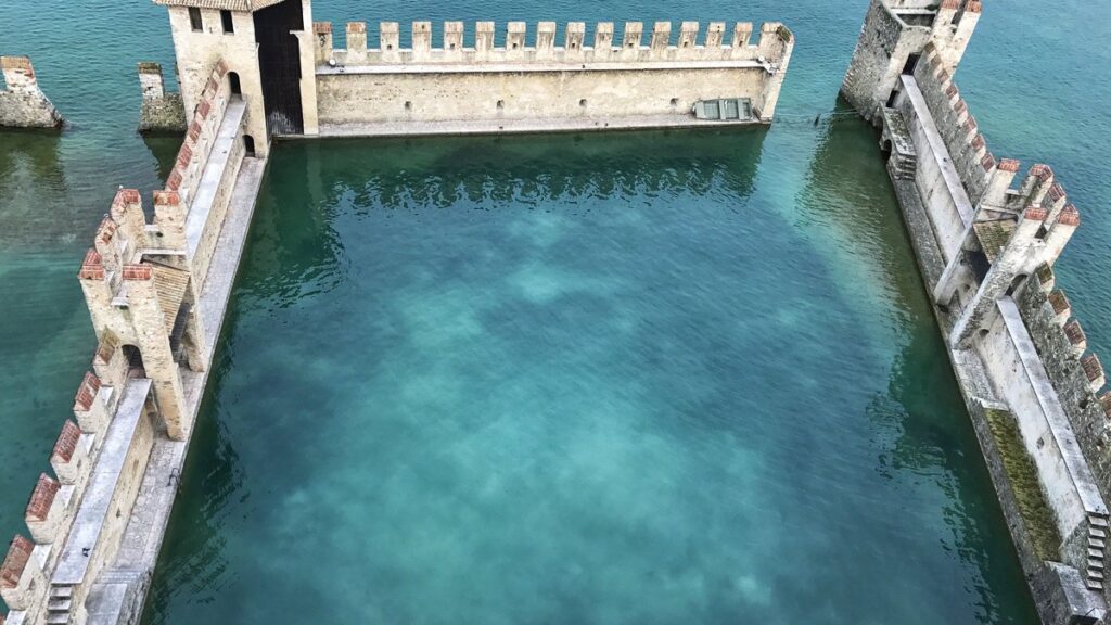 Das befestigte Hafenbecken der Scaligerburg in Sirmione mit Schwalbenschwanzzinnen und türkisem Wasser
