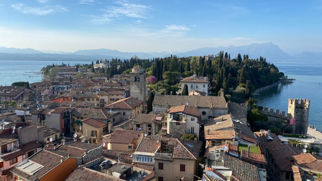 Blick über die Ziegeldächer der Altstadt von Sirmione auf die Zypressen der Halbinsel, einen Turm der Skaligerburg und den Gardasee