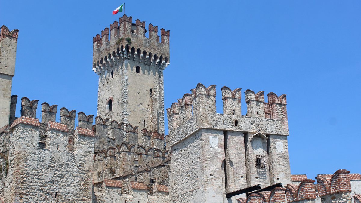 Bergfried und Schwalbenschwanzzinnen der Rocca Scaligera in Sirmione vor blauem Himmel