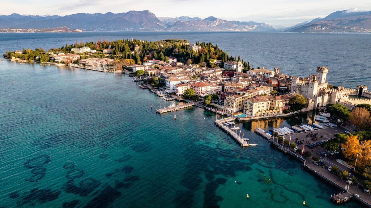 Luftbild der Halbinsel Sirmione mit der Skaligerburg und dem flachen türkisfarbenen Wasser ringsum