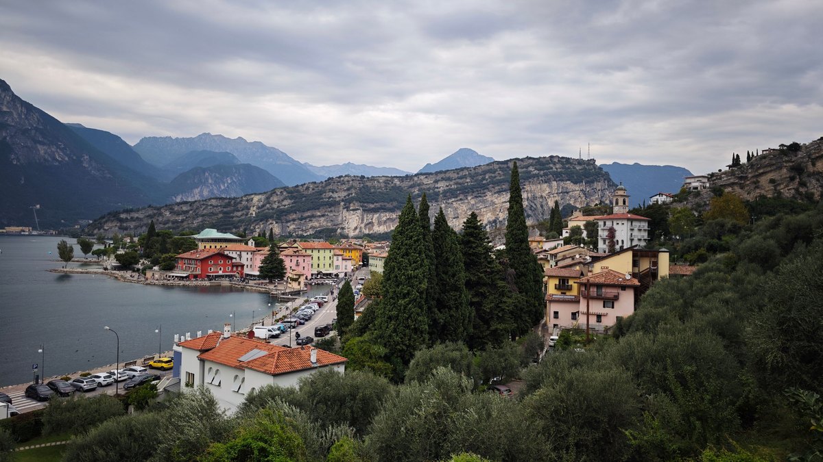 Blick über Torbole am Nordufer des Gardasees mit Uferpromenade und Bergen